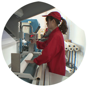 Female worker in red uniform operating a fabric processing machine in a textile factory.