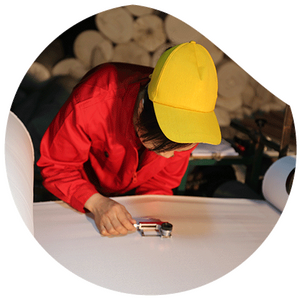 Worker inspecting the surface of white fabric with a magnifier in textile production.